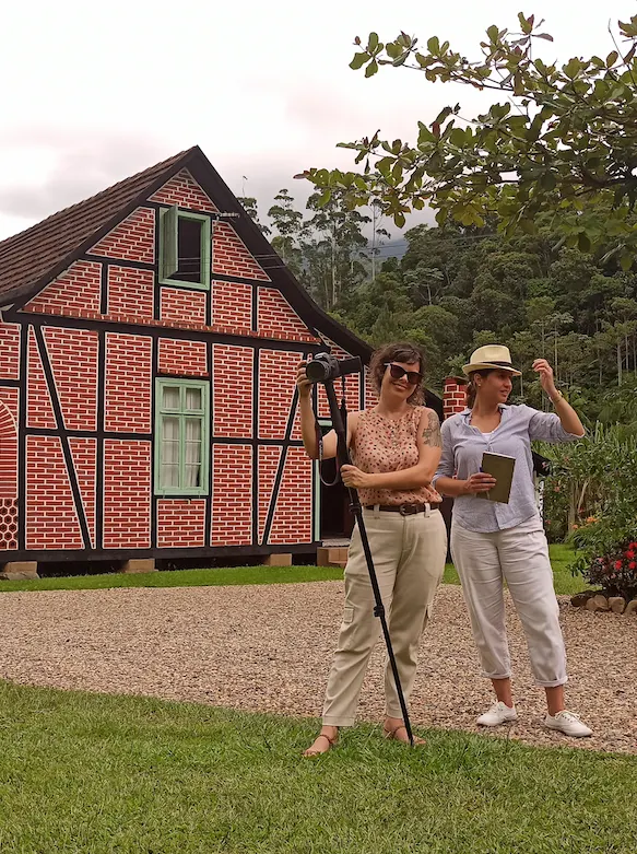 Fernanda do Canto e Carolina Bayer diante de uma casa enxaimel