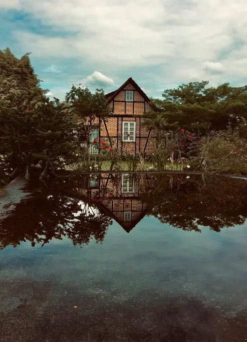 Casa enxaimel refletida na água de um lago