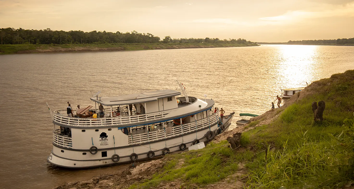 Barco do projeto Um Piano na Amazônia ancorado na margem do rio ao entardecer